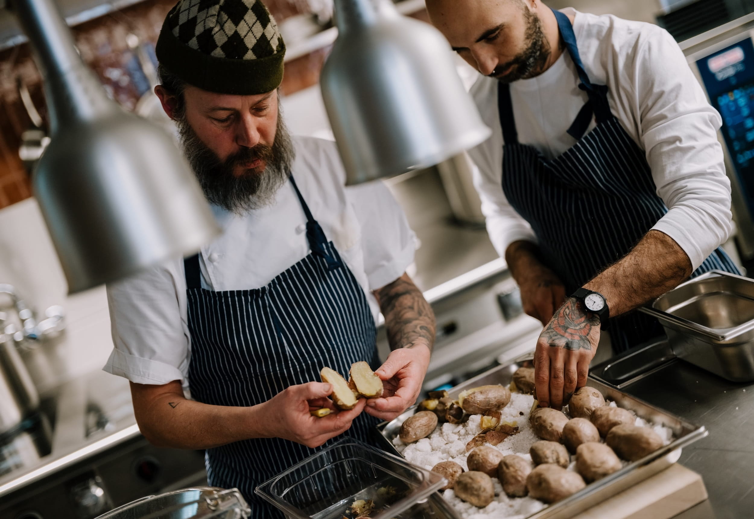 Two chefs in the kitchen cutting potatoes for the gnocchi